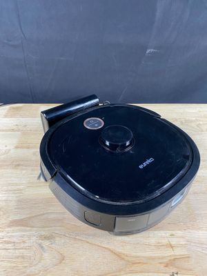un aspirateur robot noir posé sur une table en bois