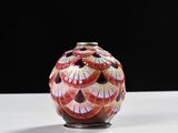 un vase rouge et blanc posé sur une table blanche