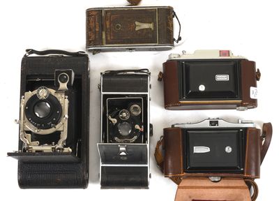 four old cameras sitting next to each other on a white surface