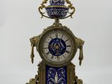 a clock that is sitting on a stand with a bowl on top