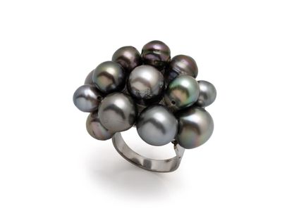 un gros plan d'une bague ornée de perles noires sur fond blanc