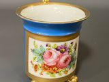 a close up of a small blue and gold container with flowers on it
