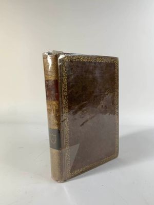 un vieux livre posé sur une table blanche à côté d'un mur blanc