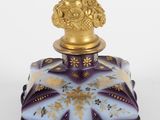 un gros plan sur un flacon de parfum violet et doré, muni d'un bouchon doré