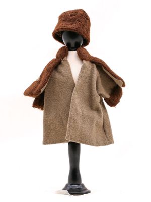 une poupée vêtue d'un manteau marron et d'un chapeau marron, posée sur un mannequin