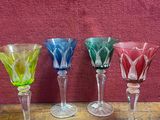 Quatre verres à vin sont alignés sur une table devant un mur rouge.