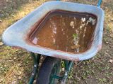 an old wheelbarrow with mud in it sitting on the ground