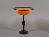 an orange and blue glass bowl on a black stand