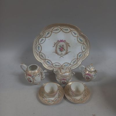 une table blanche avec une assiette dorée, des tasses et des soucoupes