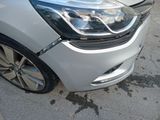 the front end of a white car with a denting dent on it ' s bumper