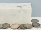 un bloc de marbre blanc avec des pièces de monnaie posé sur une table