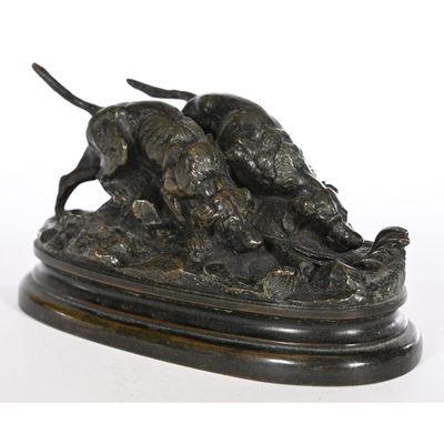 bronze statue of two dogs on a rock with a white background
