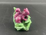 une petite figurine représentant un écureuil rose posé sur une feuille