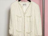 La veste blanche est suspendue à un porte-manteau devant un mur rayé de rose et de blanc.