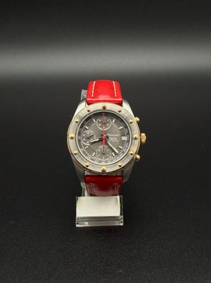montre argentée et rouge posée sur une surface noire, sur fond noir