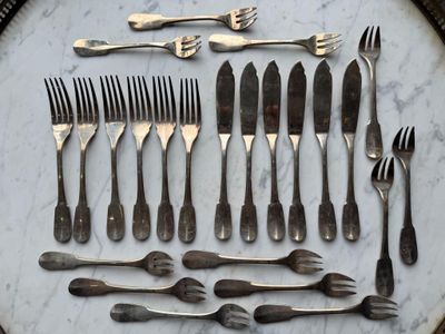 many forks and spoons laid out on a marble table