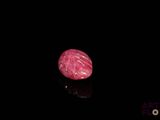 a close up of a pink stone on a black surface