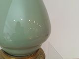 a green vase sitting on top of a glass table