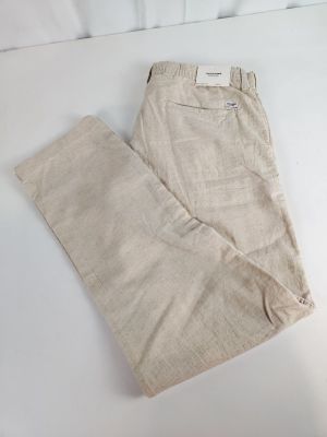 un pantalon beige posé sur un lit, avec un oreiller blanc et un autre oreiller blanc