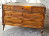 a wooden chest of drawers on a brick floor
