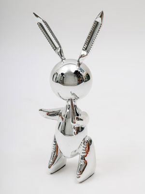 figurine de lapin en métal argenté posée sur une surface blanche, avec un fond blanc
