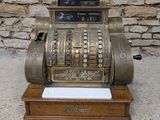 an old fashioned cash register sitting on top of a wooden stand