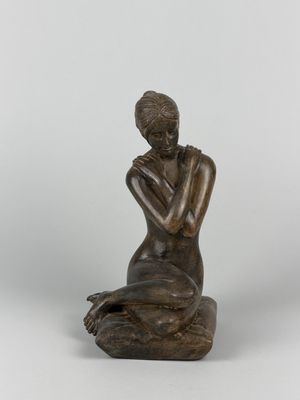 a bronze statue of a woman sitting on a rock