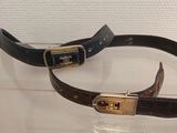 pair of brown and black leather belts with gold buckles on display