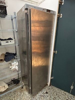 a silver refrigerator in the corner of a room next to a green door
