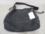 grey crocheted purse with black strap and tag on it