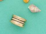 une bague en or ornée d'un coquillage, à côté d'autres bagues