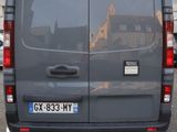 a grey van parked in a parking lot with other cars