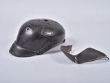 un vieux casque de baseball dont la visière est cassée, posé sur une surface blanche