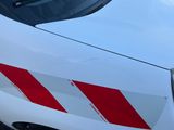 une voiture blanche avec des bandes rouges garée sur un parking