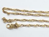 a close up of two gold chains on a white surface