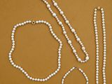 a white bead necklace and a pair of scissors on a brown surface