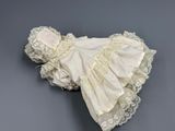an antique white dress and bonnet with lace on a gray surface