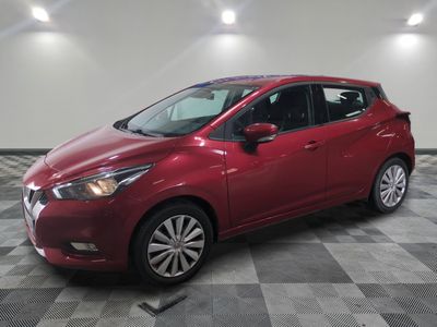 une Nissan Versa rouge garée sur un sol en carrelage à damier