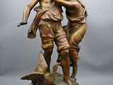 statue en bronze représentant un garçon et une fille avec un oiseau