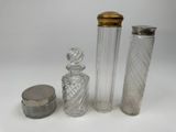 trois bouteilles en verre et un récipient en métal posés sur une surface blanche