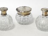 three glass bottles with silver lids sitting on top of a white surface