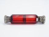un gros plan d'une bouteille en verre rouge posée sur une surface blanche