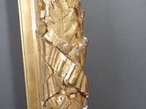 a tall gold mirror with a gold leaf design