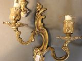a gold wall sconce with two candles on it