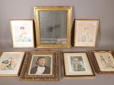 de nombreux tableaux encadrés posés sur une table, à côté d'un miroir