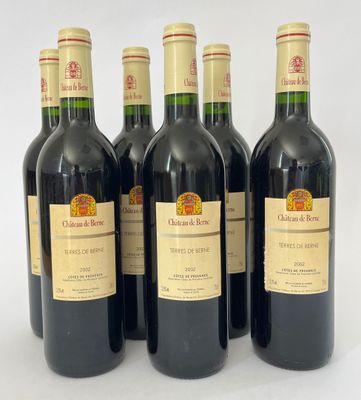 six bouteilles de vin rouge sont alignées sur une surface blanche