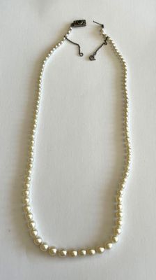 gros plan d'un collier de perles sur une surface blanche