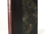 an old book with a brown cover sitting on top of a white table