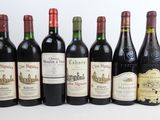 six bouteilles de vin sont alignées sur une surface blanche