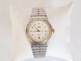 une montre en argent et en or posée sur un coussin blanc